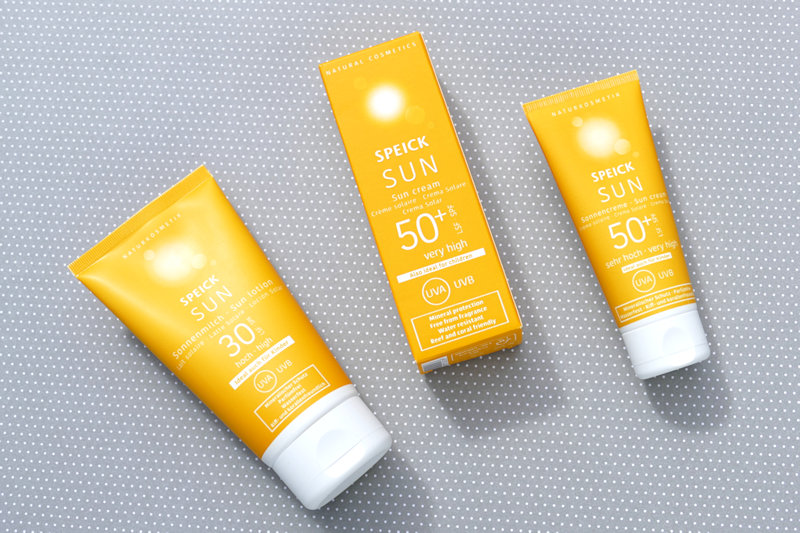 Speick Sonnenmilch LSF30 und Speick Sonnencreme LSF50 mit Karton liegen auf grauem Karton mit weißen Punkten